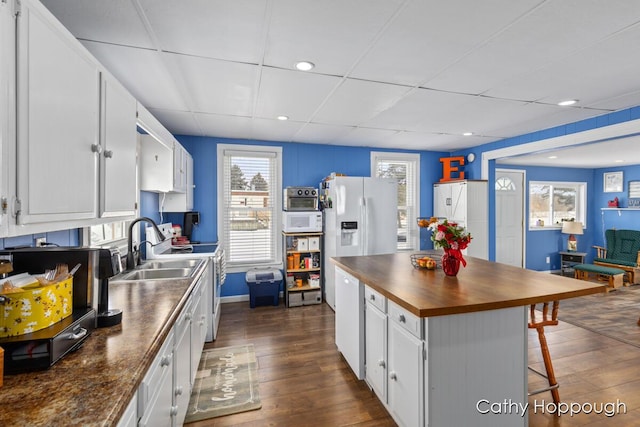 kitchen featuring a paneled ceiling, a breakfast bar area, a center island, dark hardwood / wood-style flooring, and white cabinetry