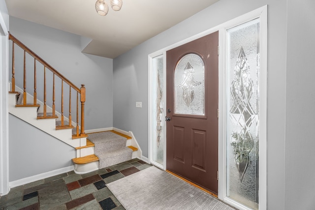 foyer featuring stairway and baseboards