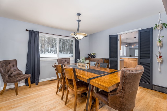 dining room featuring light wood-style floors, visible vents, and baseboards