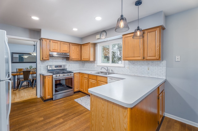 kitchen featuring under cabinet range hood, white appliances, wood finished floors, a sink, and light countertops