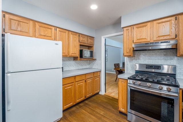 kitchen with stainless steel appliances, light countertops, dark wood finished floors, and under cabinet range hood