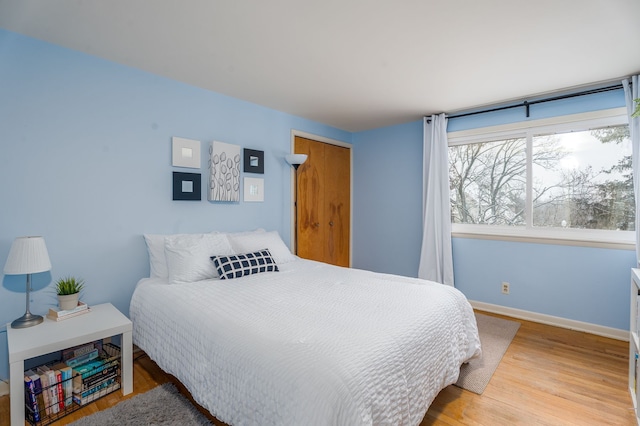 bedroom with a closet, baseboards, and wood finished floors