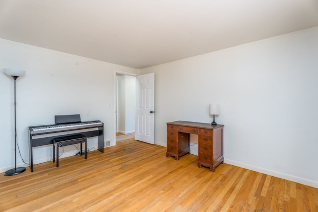 office featuring light wood-type flooring, visible vents, and baseboards