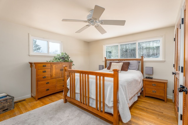 bedroom with baseboards, visible vents, a ceiling fan, and light wood-style floors