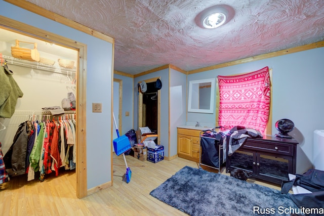 bedroom with light wood-type flooring, a closet, and ornamental molding