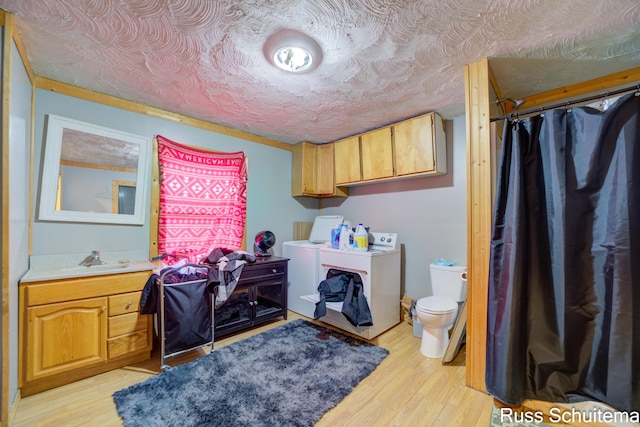 clothes washing area featuring light hardwood / wood-style floors, sink, and separate washer and dryer