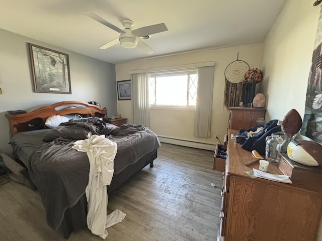 bedroom with a baseboard heating unit, hardwood / wood-style floors, and ceiling fan