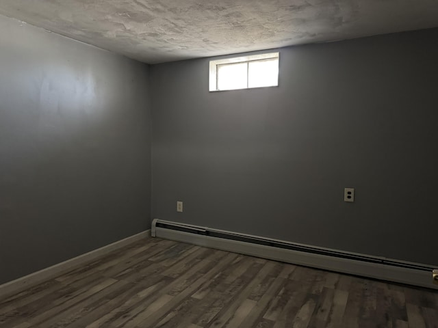 empty room featuring hardwood / wood-style flooring, a textured ceiling, and a baseboard radiator