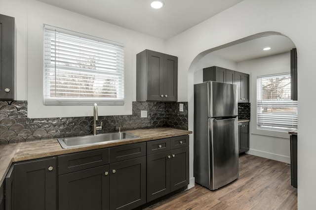 kitchen with stainless steel refrigerator, wood-type flooring, sink, and backsplash