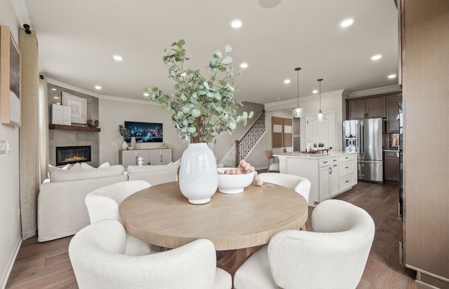 dining space with ornamental molding, a large fireplace, and dark hardwood / wood-style floors