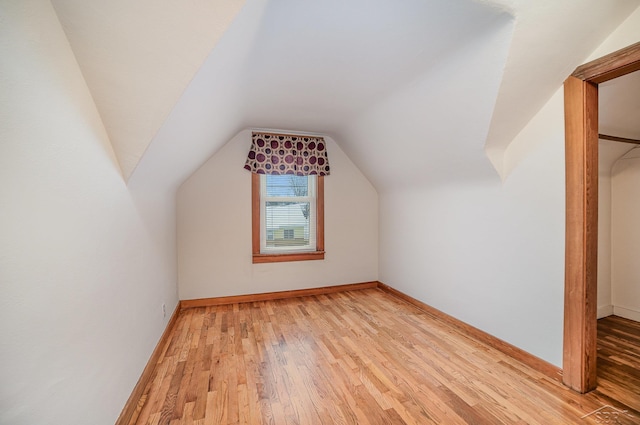 additional living space with light wood-type flooring and vaulted ceiling