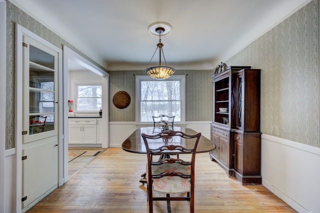 dining room with wainscoting, light wood-style flooring, and wallpapered walls