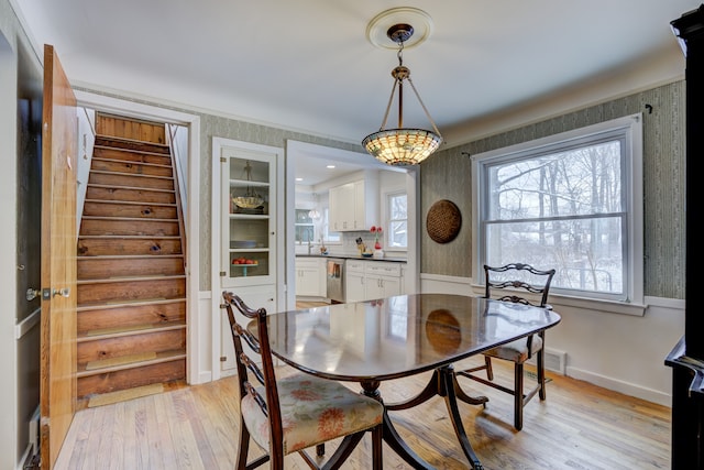 dining area featuring light wood finished floors, visible vents, stairs, and baseboards