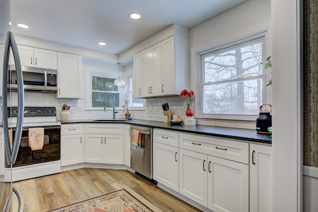 kitchen with white cabinetry, light wood-style flooring, appliances with stainless steel finishes, and a sink