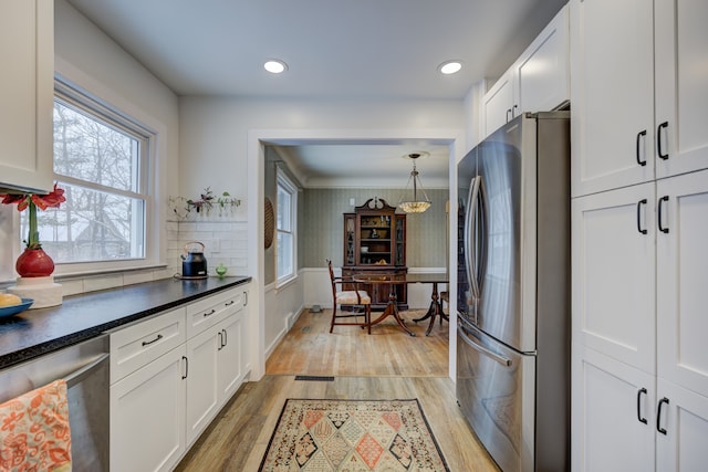 kitchen with light wood finished floors, dark countertops, recessed lighting, appliances with stainless steel finishes, and white cabinets