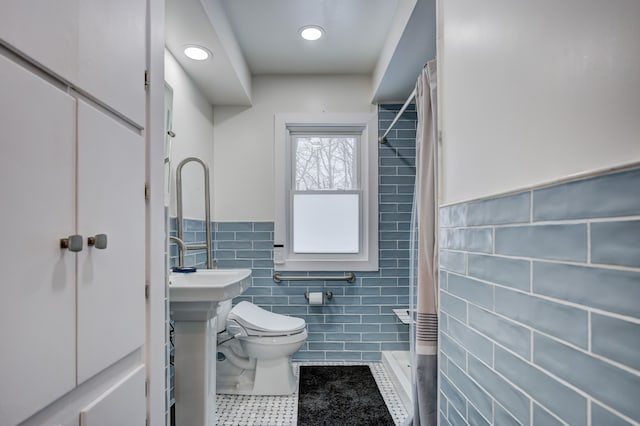 bathroom featuring a wainscoted wall, tile walls, toilet, a shower stall, and tile patterned floors