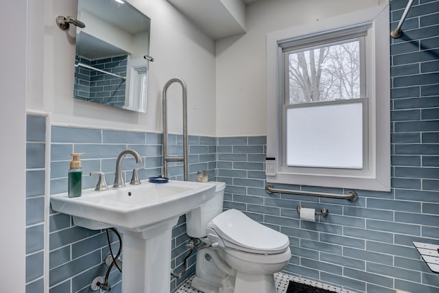 bathroom featuring wainscoting, tile walls, and toilet