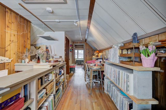 interior space with vaulted ceiling, wood walls, track lighting, and wood finished floors