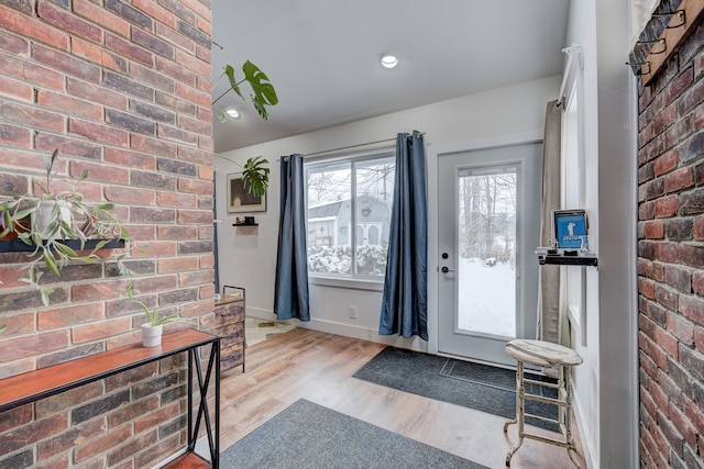 foyer featuring brick wall, baseboards, wood finished floors, and recessed lighting