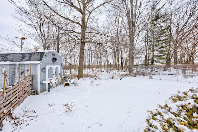 yard covered in snow featuring a storage unit, fence, and an outbuilding