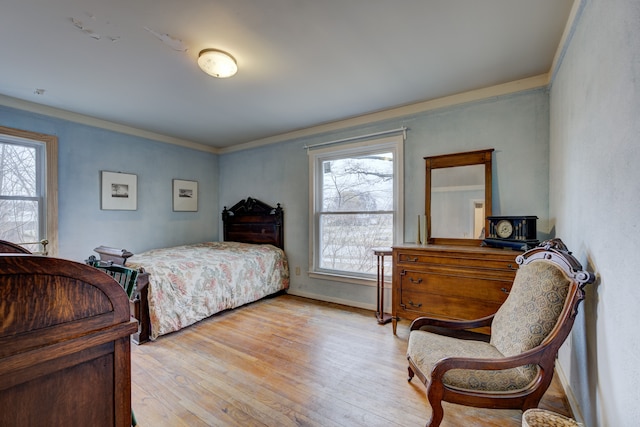 bedroom with light wood-style floors, ornamental molding, and baseboards