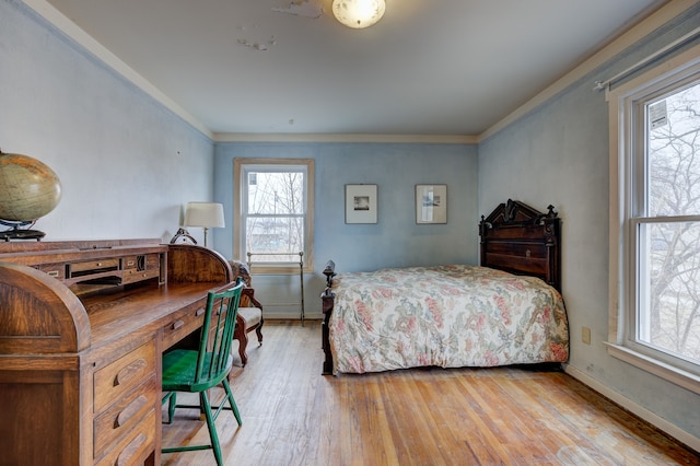 bedroom featuring baseboards, wood finished floors, and ornamental molding