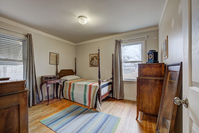 bedroom featuring baseboards, light wood finished floors, visible vents, and crown molding