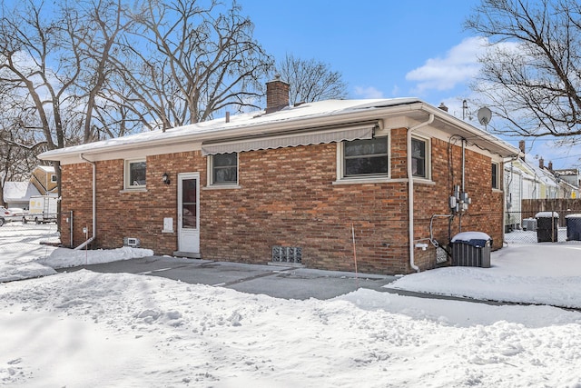 snow covered back of property with central AC