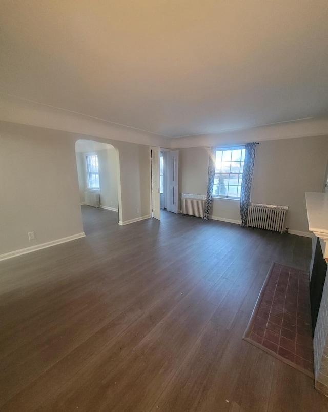 unfurnished living room with radiator heating unit and dark hardwood / wood-style floors