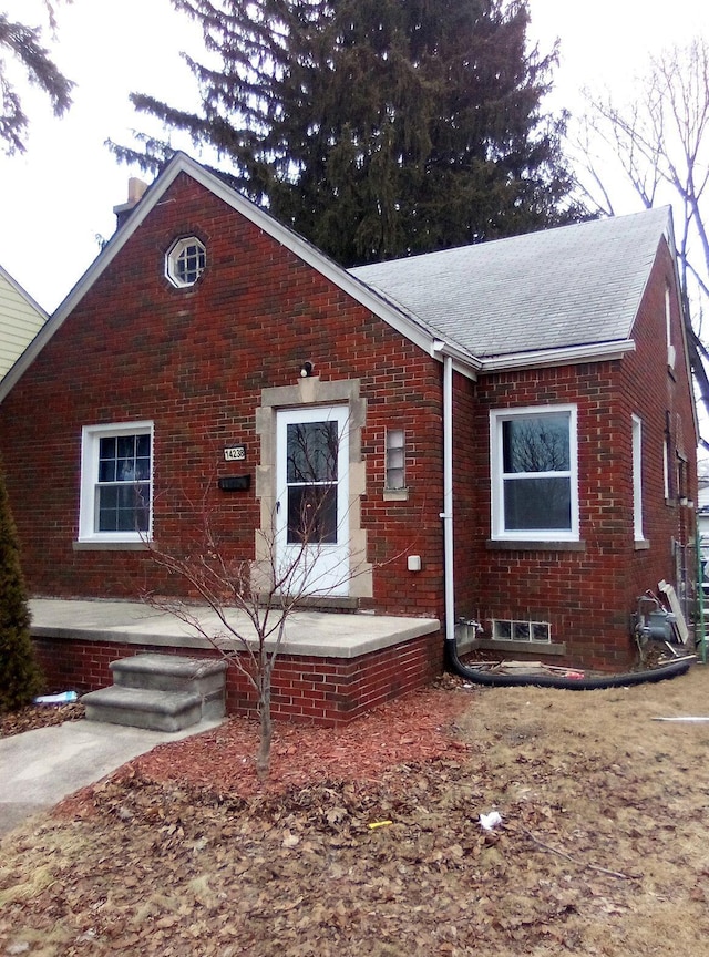 view of front of property featuring a shingled roof and brick siding