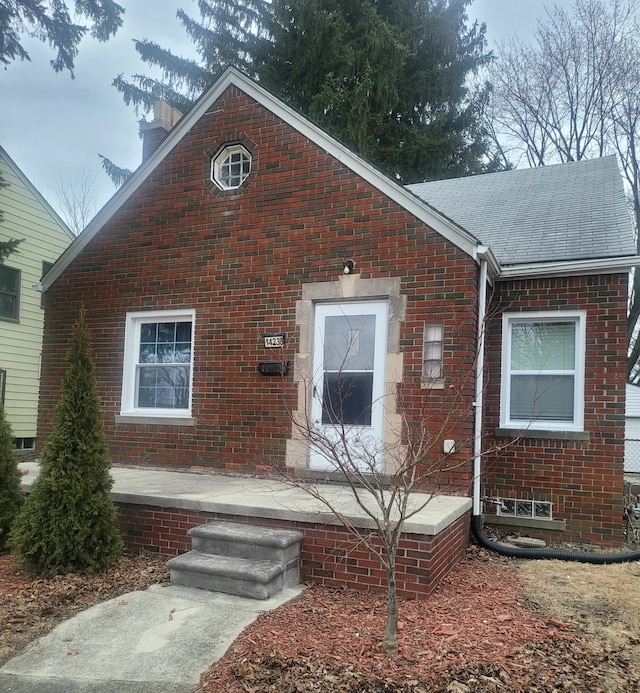 view of front of house featuring brick siding, a chimney, and roof with shingles