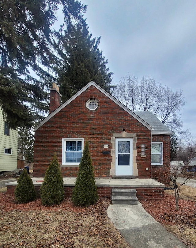 bungalow-style home with brick siding and a chimney