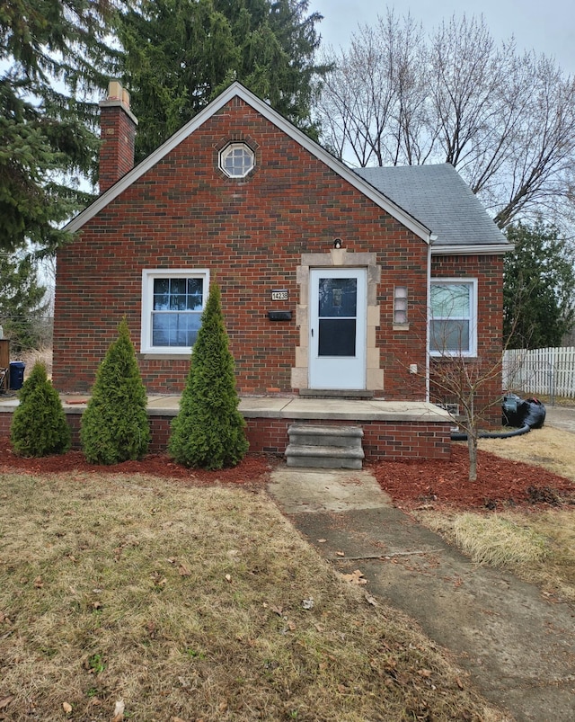 view of front of home with a front lawn, fence, brick siding, and a chimney