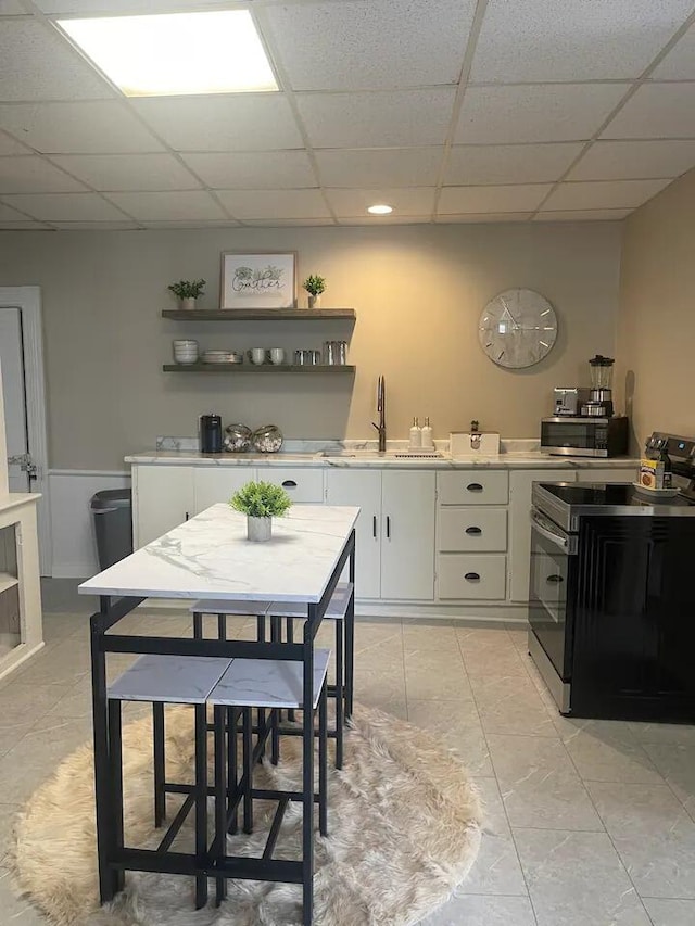 kitchen with a drop ceiling, sink, white cabinetry, and stainless steel appliances