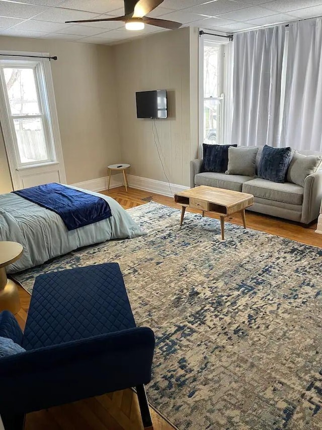 bedroom with multiple windows, hardwood / wood-style flooring, a paneled ceiling, and ceiling fan