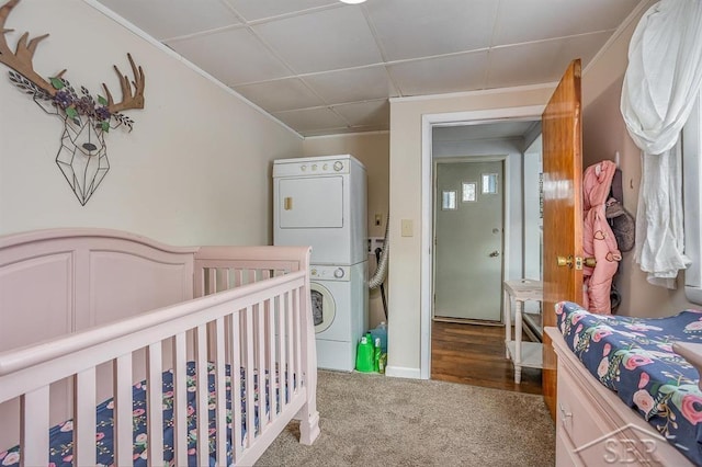 carpeted bedroom with stacked washer and dryer and a drop ceiling