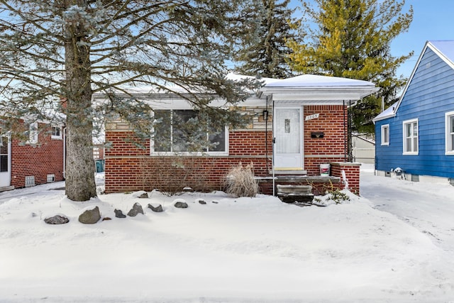 bungalow-style home with entry steps and brick siding