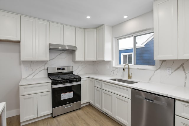 kitchen with sink, white cabinets, stainless steel appliances, and light hardwood / wood-style flooring