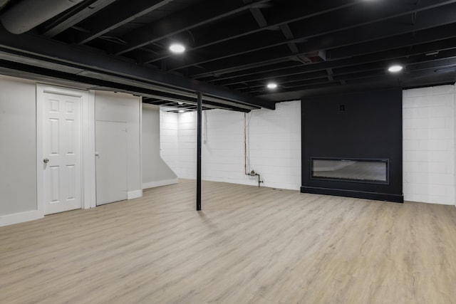 basement with a large fireplace and hardwood / wood-style floors