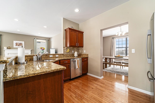 kitchen with sink, backsplash, light stone counters, light hardwood / wood-style floors, and stainless steel appliances