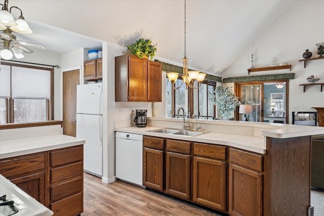 kitchen with white appliances, lofted ceiling, pendant lighting, ceiling fan with notable chandelier, and sink