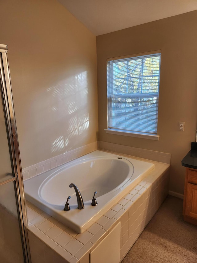 bathroom featuring vanity and a relaxing tiled tub