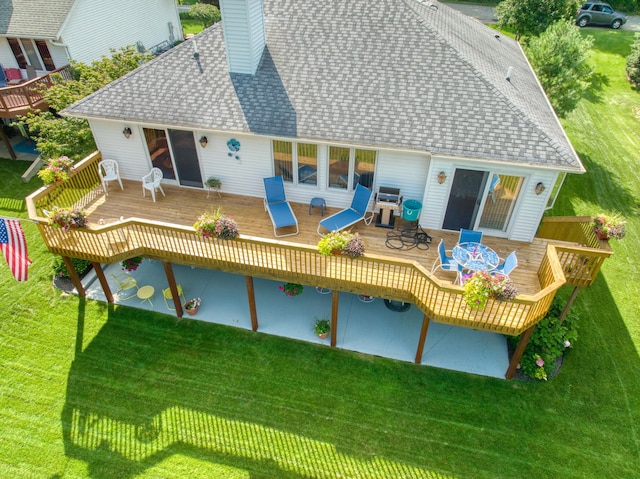 rear view of house featuring a lawn and a wooden deck