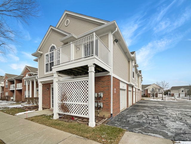 view of side of home with a garage and a balcony