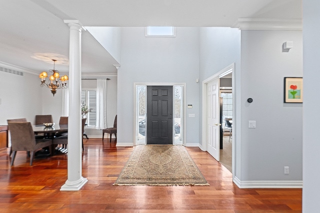 foyer entrance featuring plenty of natural light, crown molding, decorative columns, and hardwood / wood-style floors