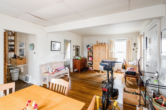 dining space featuring dark wood-type flooring, a drop ceiling, visible vents, and baseboards