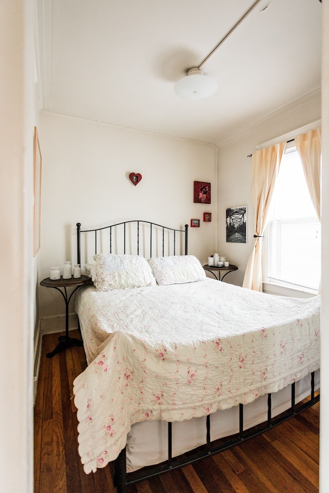 bedroom with crown molding and wood finished floors