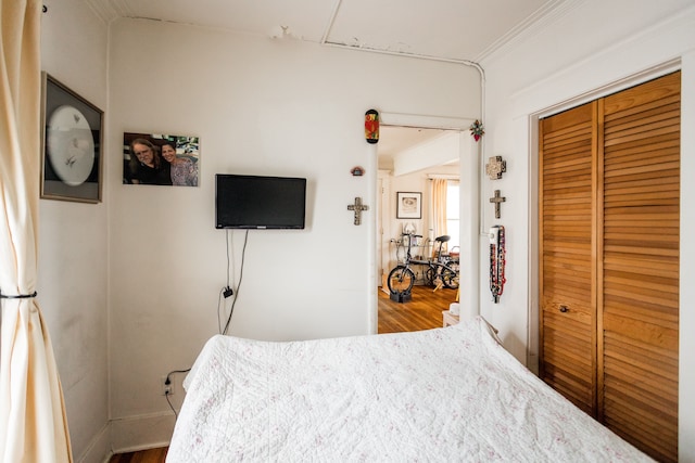 bedroom with ornamental molding, a closet, and wood finished floors