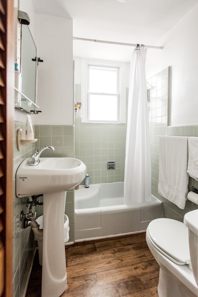 full bathroom with shower / tub combo with curtain, tile walls, toilet, and wood finished floors