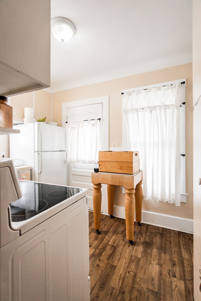 kitchen with white appliances, dark wood finished floors, white cabinets, and baseboards